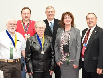 group of five people with medals