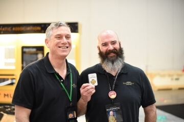 two men, one holding up a graded gold coin