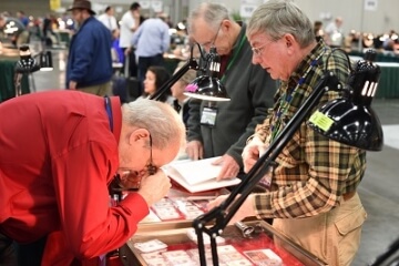 man examining a coin at a show