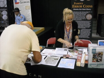 man bent over a coin show booth