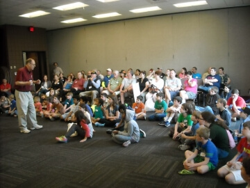 man presenting to large group sitting on floor