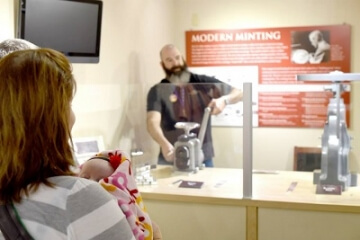 man demonstrating coining press at the money museum