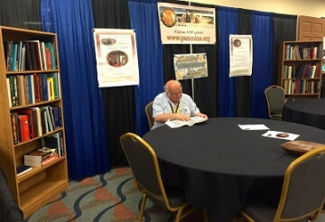 man at table with bookshelf