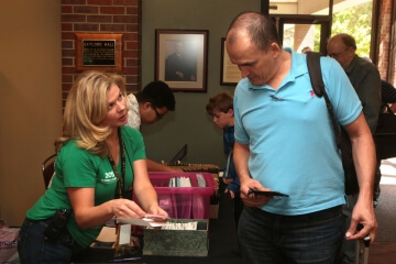 woman going through box of badges at summer seminar