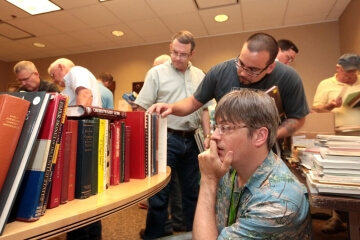 men in small library looking at books