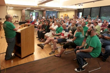 man speaking in front of large group