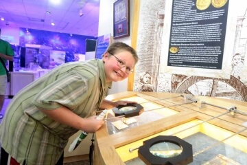 young numismatist looking at money museum exhibit