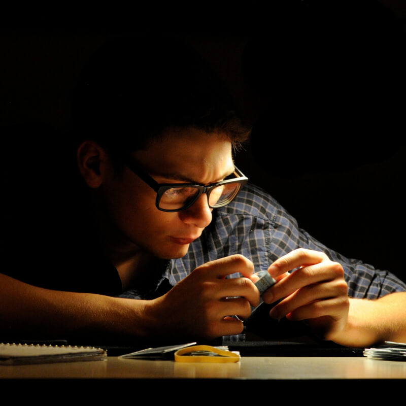 young man teen boy studying coin black bg
