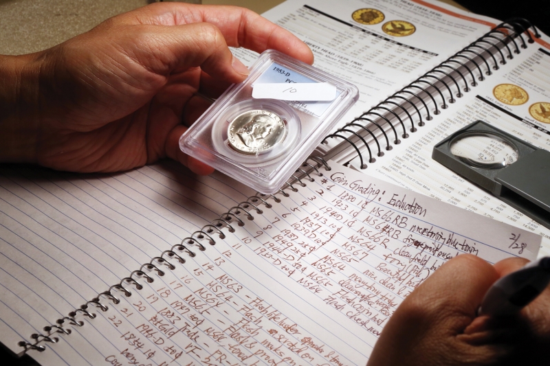 person holding graded coin over notebook