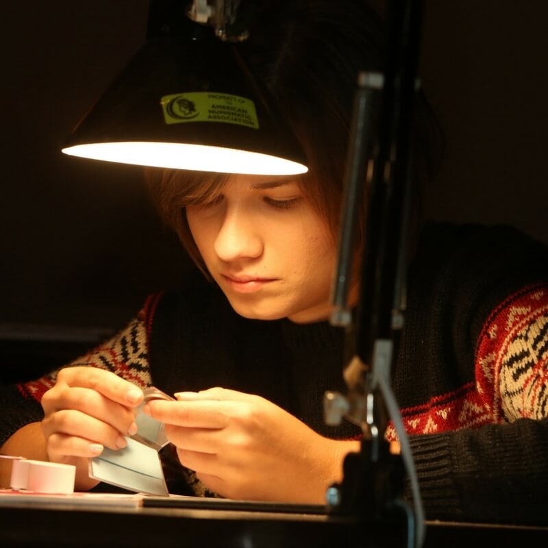 young coin collector examining coin